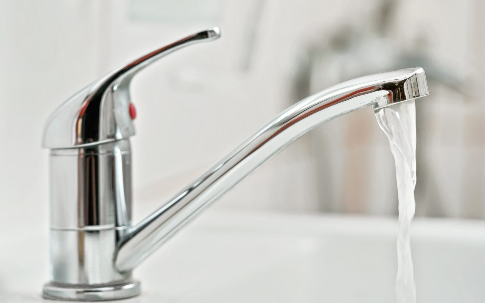 Chrome bathroom faucet with water running into the sink